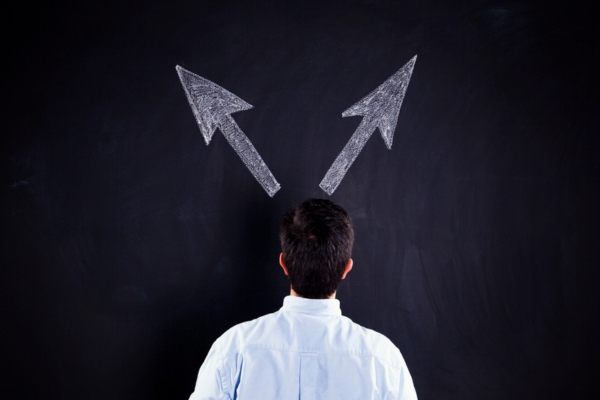 man looking at chalkboard with arrow on different directions depicting choosing between repair or replace tankless water heater