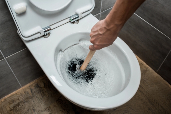 homeowner unclogging toilet after flushing down wipe