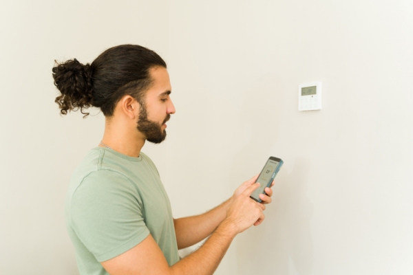homeowner synching smart thermostat on smart phone