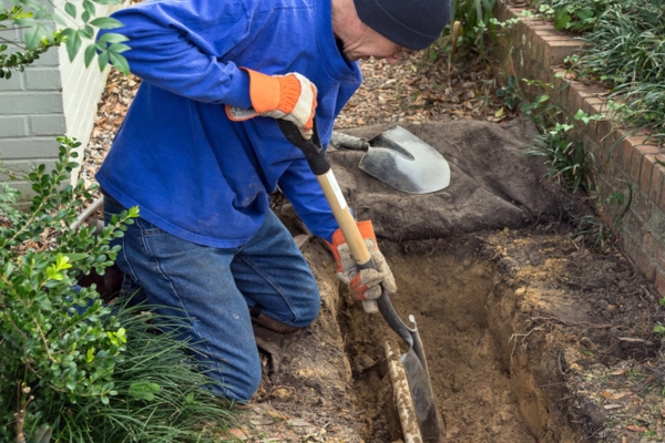 man digging beside sewer line