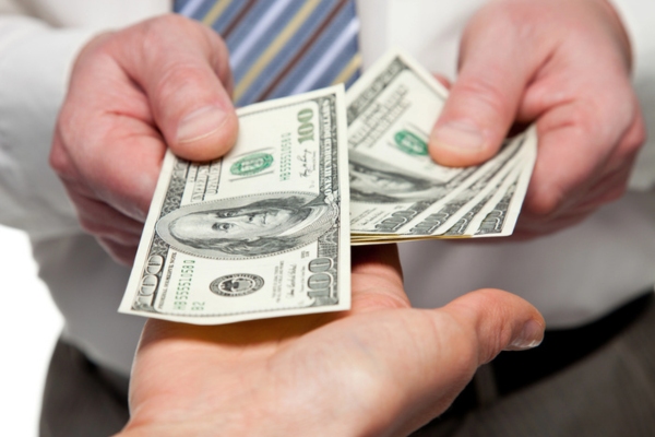 Human hands exchanging money depicting paying frequently for heating & cooling repairs