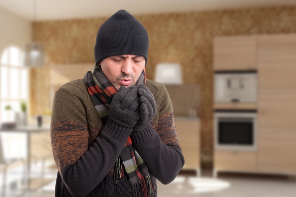 man feeling cold while wearing a full winter wear indoors due to malfunctioning heating system