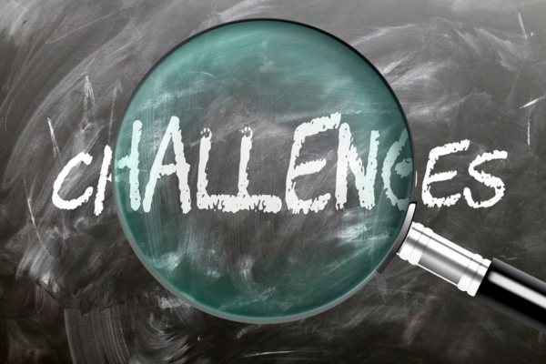 challenges written on a chalkboard highlighted by a magnifying glass
