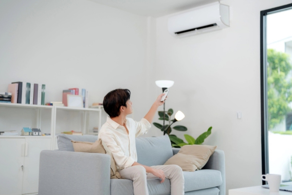 man turning on ductless air conditioner during summer