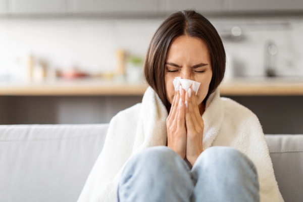 woman blowing nose on tissue due to dust and allergens