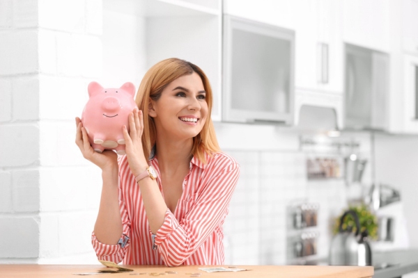 Woman with piggy bank and money at home depicting AC efficiency lowering utility cost