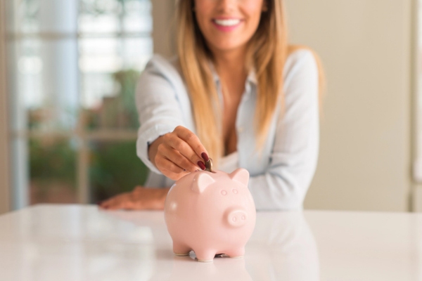 woman putting a coin in a piggy bank depicting Reduce Energy Expenses