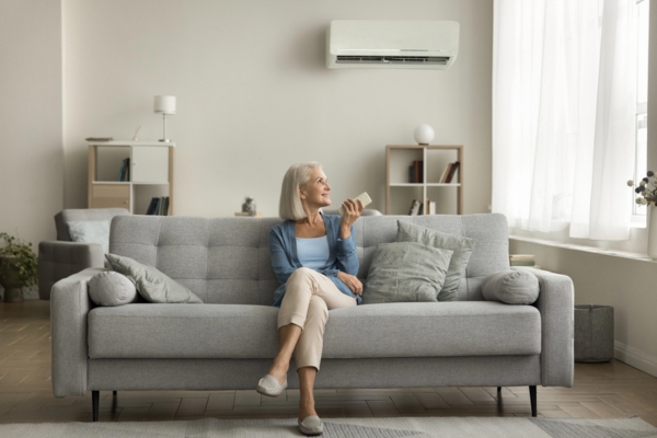woman sitting on the couch turning on ductless AC during summer