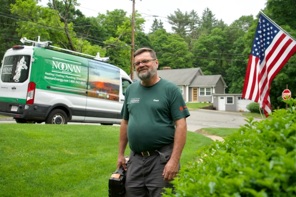 HVAC technician with the Noonan Energy service van behind him