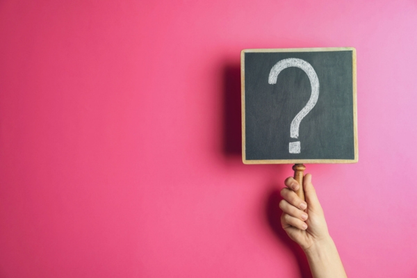 question mark on a mini chalkboard held up by a woman depicting Summer Heating Oil Tanks FAQs