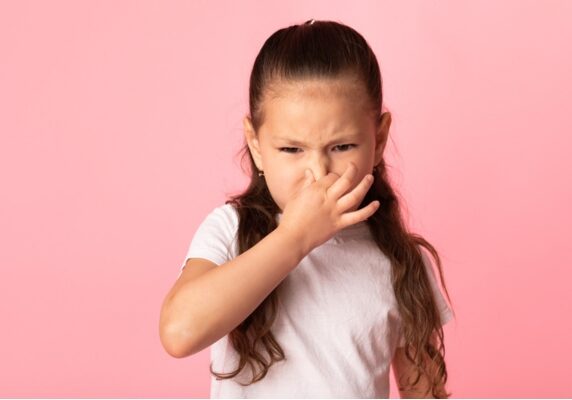 young girl covering her nose depicting sewer gas smell in house